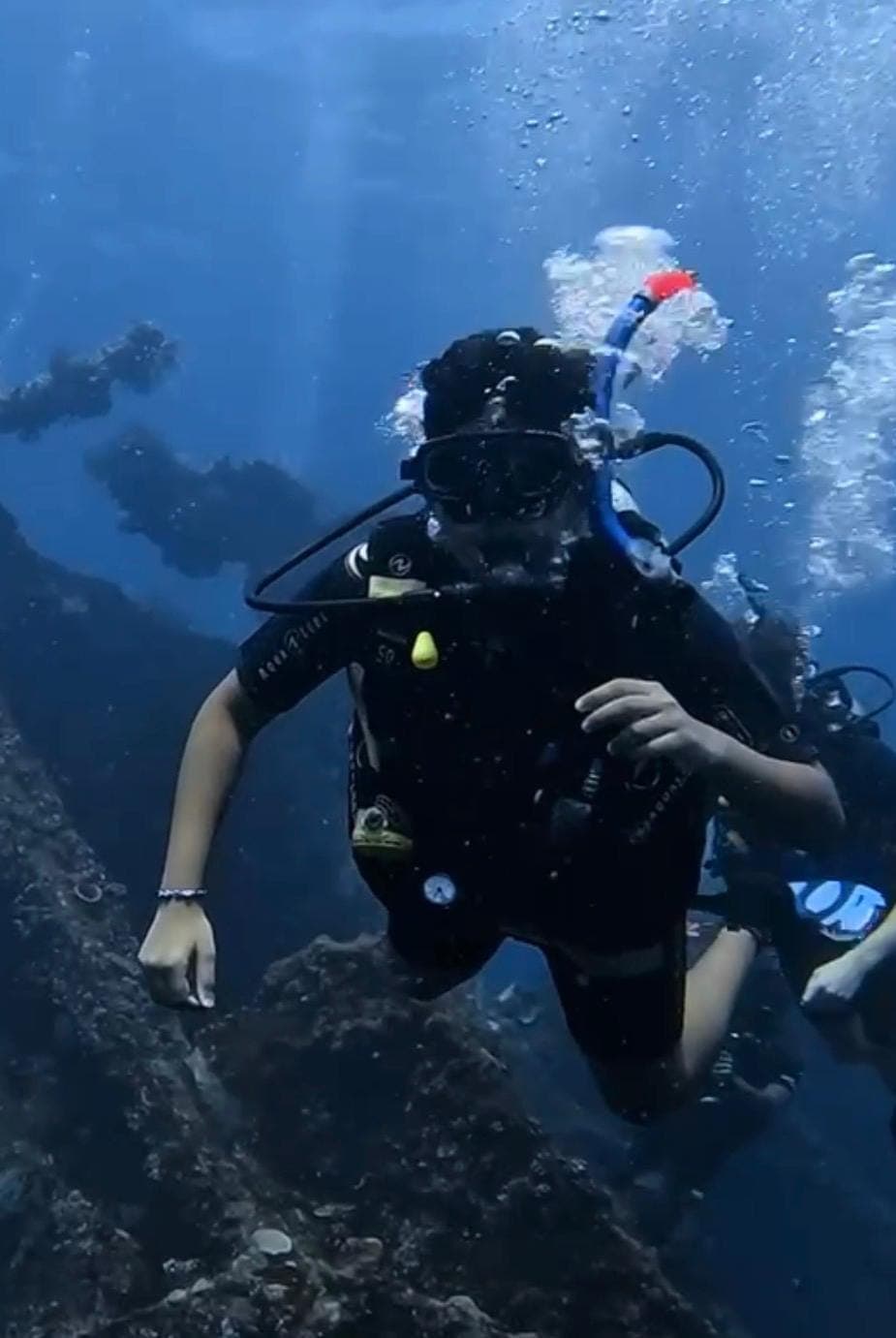 Darsh Shhaparia scuba diving underwater beside a wreck